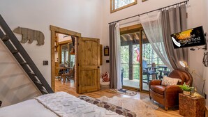 A cozy room with a bed, a wooden ladder, a leather chair, and a TV displaying 'The Lodge Nest'. - Hawks Ridge - Eagles Nest home with fireplace, amenities (Banner Elk)