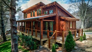 A wooden cabin with a deck, surrounded by trees. - Hawks Ridge - Eagles Nest home with fireplace, amenities (Banner Elk)