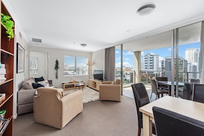 Relax in this stylish living room with a sofa, coffee table, and TV, offering a city view from the large window.