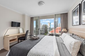 Relax in a spacious room with a large bed, desk, and city view.