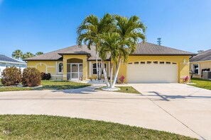 Ein Bungalow mit Garage, einer Veranda und einer Palme im Vorgarten.
