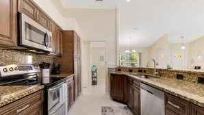 A kitchen with granite countertops, stainless steel appliances, and wooden cabinets. - Gorgeous heated pool home - Villa Palm Tree - Roelens Vacations (Cape Coral)