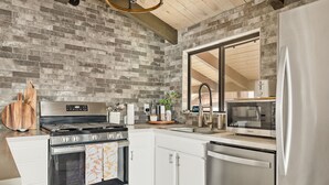 Una cocina moderna con pared de ladrillo, electrodomésticos de acero inoxidable y muebles color blanco.