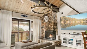 Una sala acogedora con chimenea de piedra, un televisor de pantalla plana grande y un sofá cómodo.