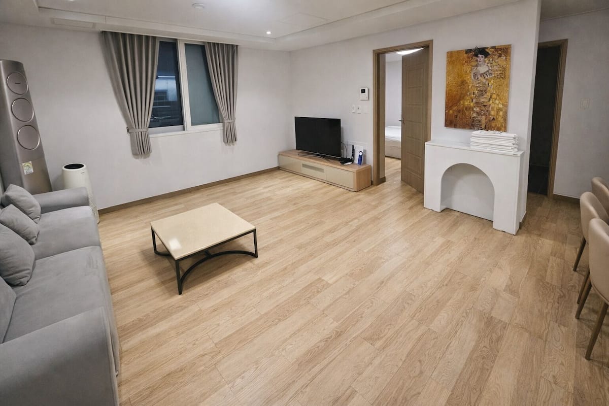 A modern living room with a sofa, a coffee table, a TV, and a painting on the wall.