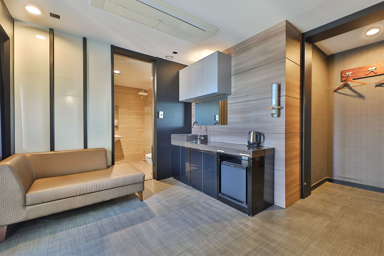 A modern kitchen with a built-in oven, a coffee machine, and a small refrigerator.