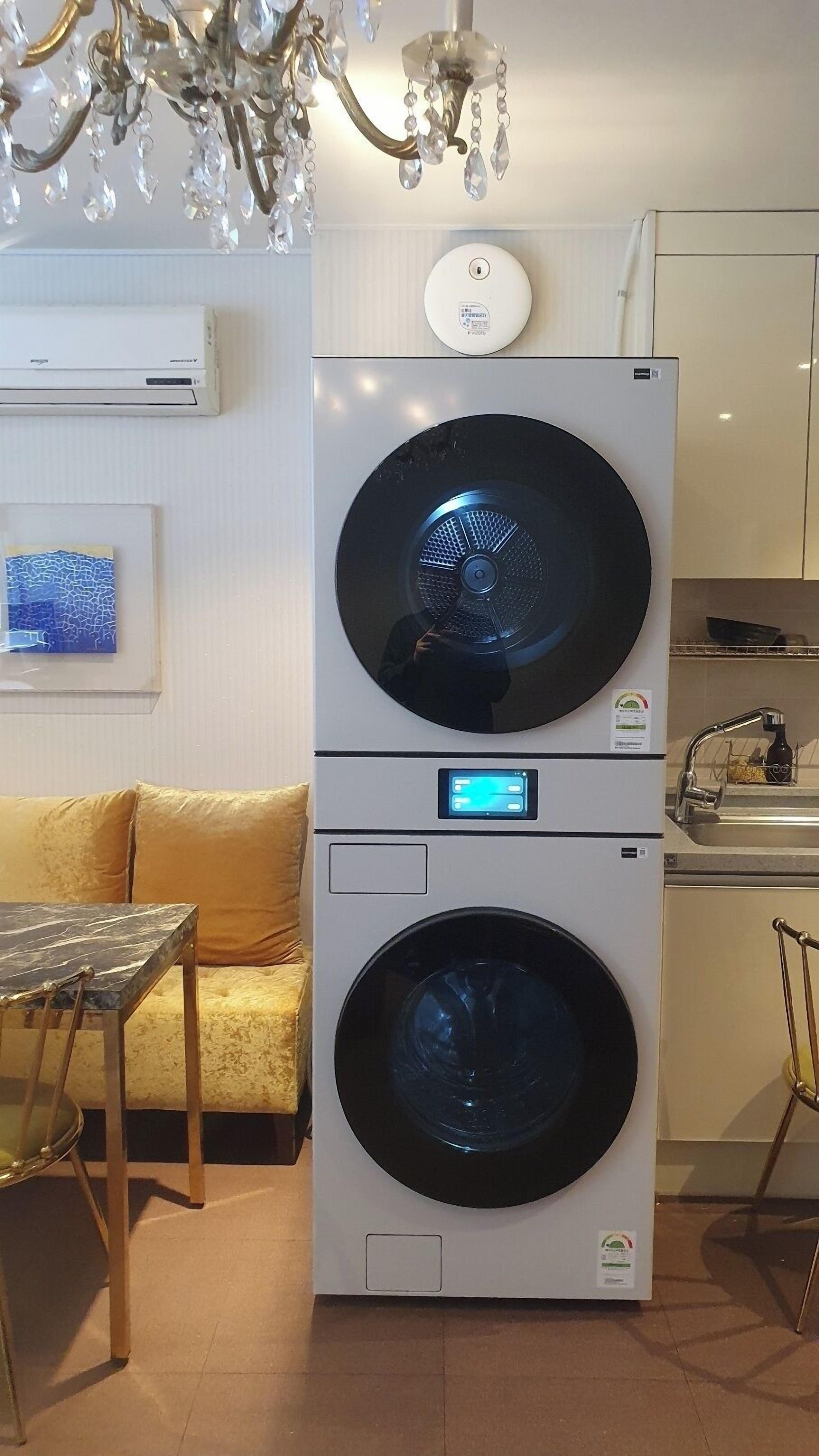A compact washer and dryer unit with a digital display, a small sink, and a chandelier.