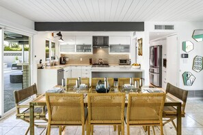 Enjoy a casual dining experience in this kitchen with a central island, stove, and dining area with a glass-top table and wicker chairs.