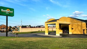 A Budgettel Inn with a yellow building and a covered parking area. - Budgetel Inn (Scottsboro)
