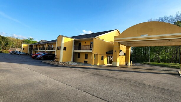 A yellow multi-story motel with a covered parking area and a visible entrance. - Budgetel Inn (Scottsboro)