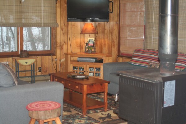 A cozy living room with a fireplace, a television mounted on the wall, and a comfortable sofa.