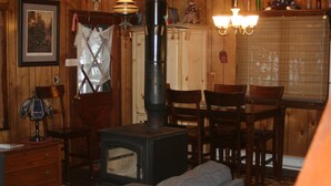 Una camera accogliente con stufa a legna, arredi in legno e zona pranzo.