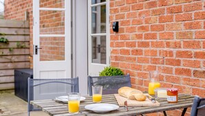 Ein Tisch im Freien mit Frühstücksangebot, darunter Brot, Butter und Orangensaft.