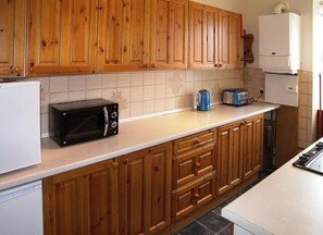 Une cuisine avec des meubles en bois, un four à micro-ondes, un grille-pain et une bouilloire.