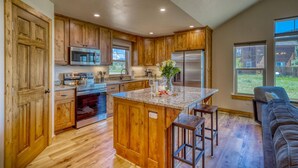 A spacious kitchen with wooden cabinets, stainless steel appliances, and a central island with stools.