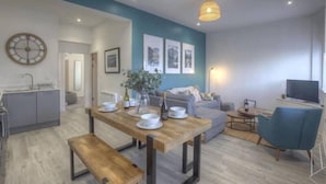 A modern living room with a wooden dining table, a blue armchair, and a sofa. - The Swell by Guestz (Rhosneigr)