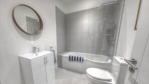 A modern bathroom with a toilet, sink, and shower. - The Swell by Guestz (Rhosneigr)