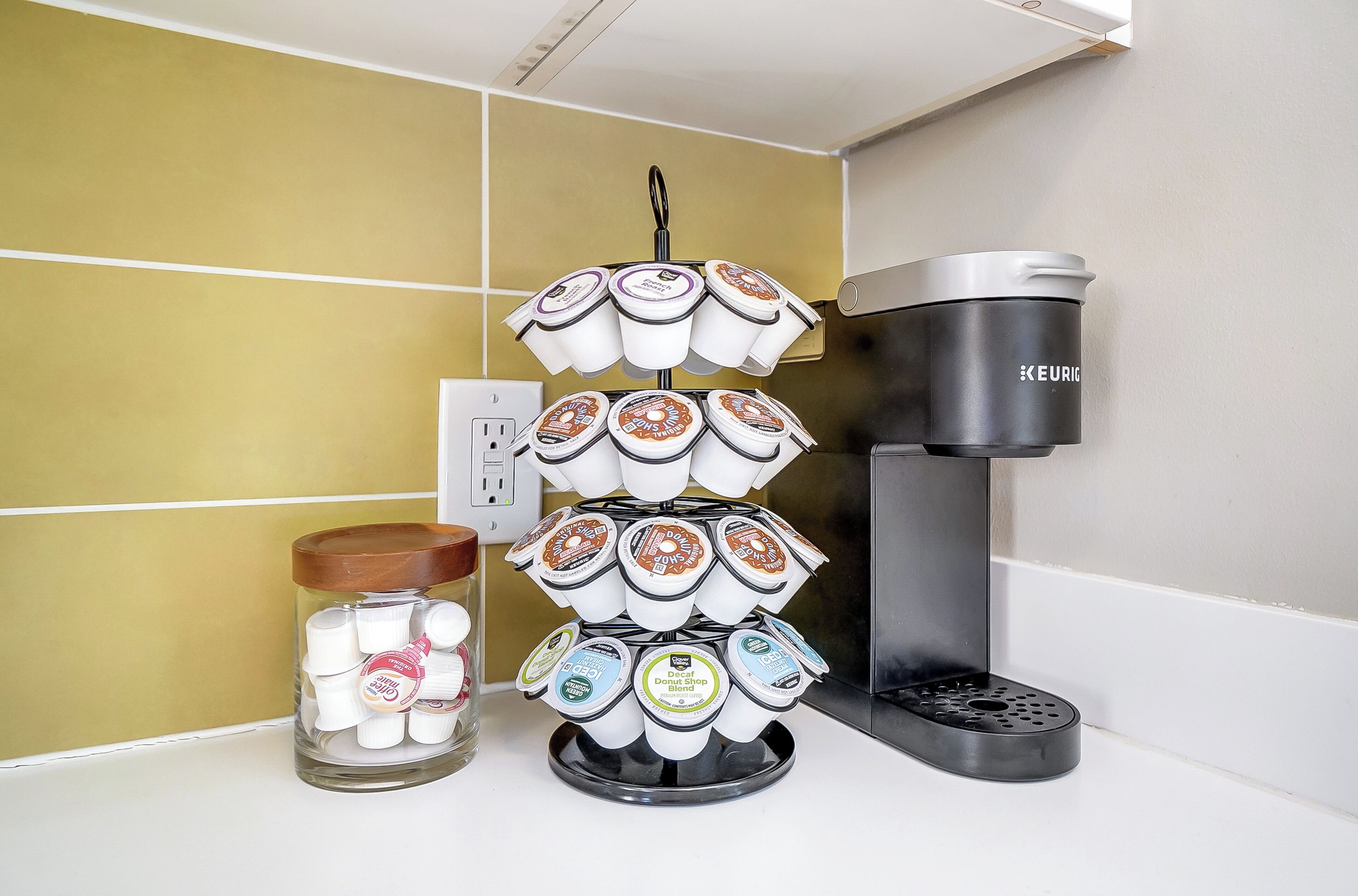A coffee maker and a coffee pod holder with multiple pods on a kitchen counter.