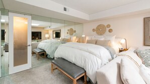 Un dormitorio moderno con una cama grande, un banco, una mesita de noche, un espejo y una pared con elementos decorativos.