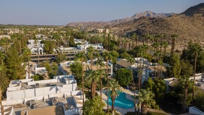 Un resort con varias edificaciones, una piscina y palmeras.
