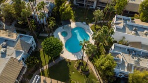 Vista aérea de una zona residencial con piscina rodeada de palmeras y un pequeño pabellón.