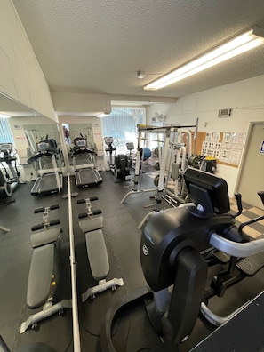 A gym with various exercise equipment, including treadmills, weight machines, and free weights.