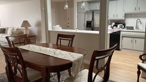 A dining area with a wooden table and chairs, a chandelier, and a view into the kitchen with modern appliances. - Beautiful Remodeled West Los Angeles condo - Brentwood adjacent.  (Los Angeles)