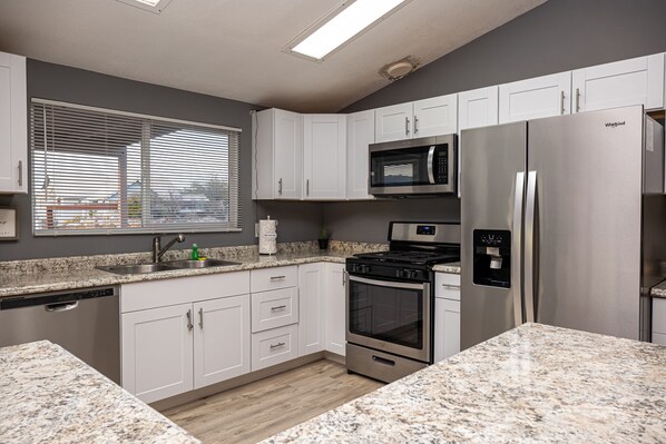 A modern kitchen with white cabinets, a stainless steel refrigerator, a built-in microwave, and a stove. - Casita Lara 🌵 Mountain Views •8 Min to Laughlin •Sleeps 6 (Bullhead City)