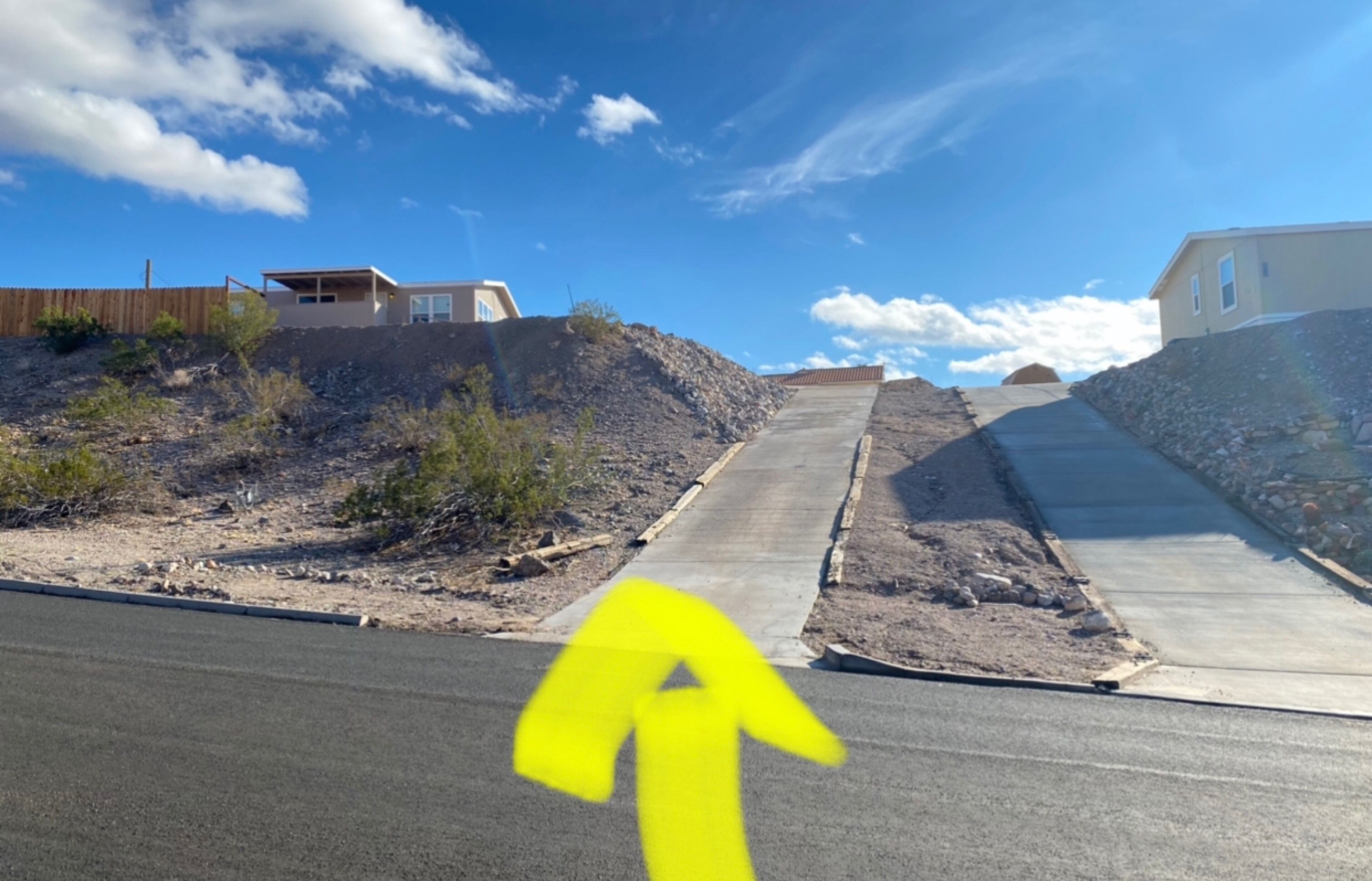 A road leading uphill with a yellow arrow pointing straight ahead.