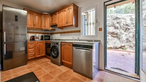 Cocina compacta con armarios de madera, electrodomésticos de acero inoxidable y lavavajillas integrado.