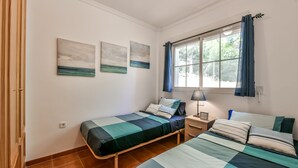 Un dormitorio con dos camas, una ventana con cortinas y tres cuadros colgados en la pared.