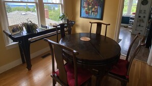 Un espace repas avec une table ronde et des chaises, un lustre et une vue dégagée grâce à de grandes fenêtres.