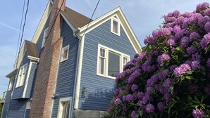 Une maison à deux étages avec une cheminée en briques, des encadrements de fenêtres blancs et un revêtement extérieur bleu.