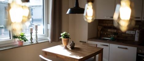 A kitchen with a wooden table, white cabinets, and hanging pendant lights.