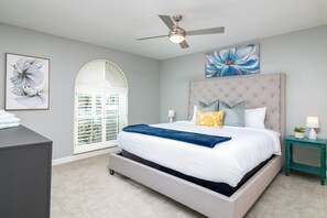 Relax in this serene bedroom with a large bed, tufted headboard, and comfortable pillows.
