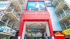 A cinema with a prominent red and blue facade, featuring a large advertisement for 'Vishaal Mal' and 'All-in-One Family Entertainment Destination'. - Aishwaryam Hotel (Madurai)