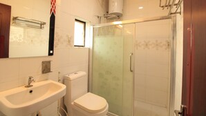 A bathroom with a sink, toilet, and glass-enclosed shower. - Aishwaryam Hotel (Madurai)