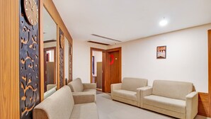 A modern living room with two sofas and a large mirror. - Aishwaryam Hotel (Madurai)