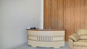 A small, wooden desk with a chair, a wall socket, and a wooden panel. - Treebo Alankar Hoshangabad Road (Bhopal)