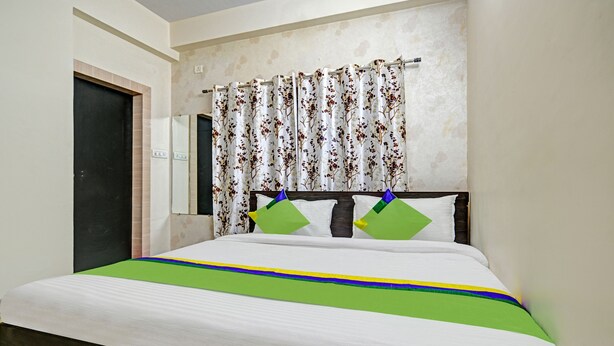 A bedroom with a bed, floral curtains, and a headboard. - Treebo Alankar Hoshangabad Road (Bhopal)