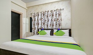 A bedroom with a bed, floral curtains, and a headboard.