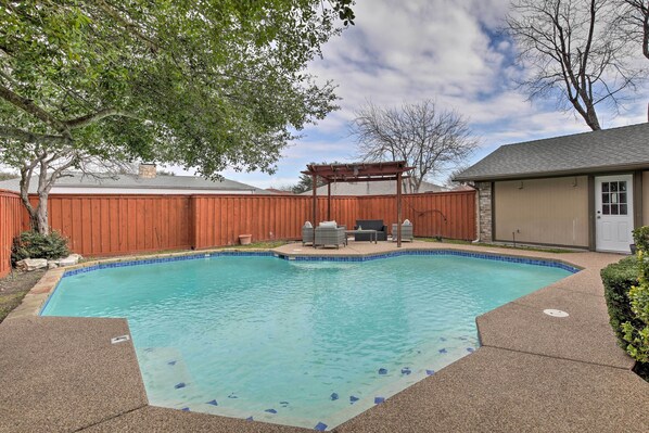 A backyard with a swimming pool, a wooden fence, and a covered patio area. - Game Room & Private Pool: Richardson Retreat (Richardson)
