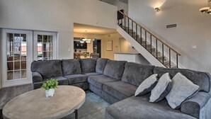 A spacious living room with a sectional sofa, a round coffee table, and a staircase leading to an upper level. - Game Room & Private Pool: Richardson Retreat (Richardson)