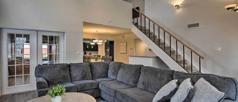 A spacious living room with a sectional sofa, a round coffee table, and a staircase leading to an upper level.
