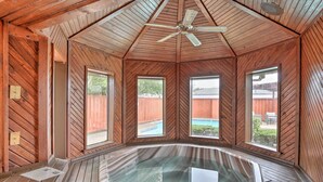 A wooden cabin with a hot tub, large windows, and a ceiling fan. - Game Room & Private Pool: Richardson Retreat (Richardson)