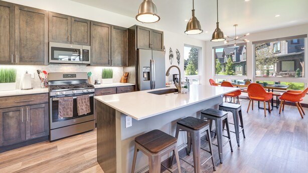 Une cuisine moderne avec des meubles en bois foncé, des appareils en acier inoxydable et un grand îlot central doté de tabourets de bar.