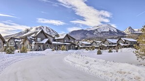 Une route enneigée menant à une rangée de chalets en bois, avec une montagne en toile de fond.