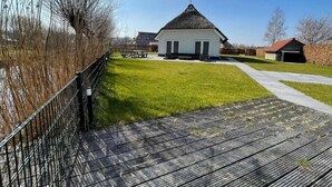 Un edificio blanco con techo a dos aguas, un sendero pavimentado y una zona ajardinada con una mesa de picnic.