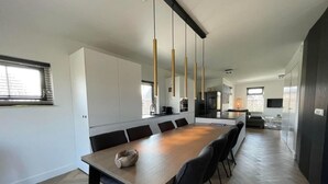Una cocina moderna con una isla grande, luces colgantes y un comedor con sillas.
