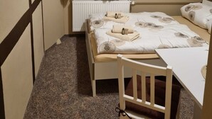 Pieni, siististi järjestetty makuuhuone, jossa on yksi s änky, tuoli, pieni pöytä ja ikkuna, jossa on verhot.